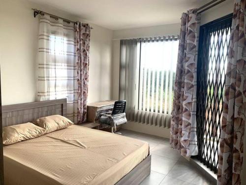 a bedroom with a bed and windows and a chair at Évasion Tropicale à 5 min des Plages in Albion