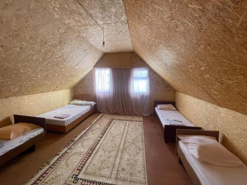 an attic room with three beds and a window at Иртыш in Borovoye