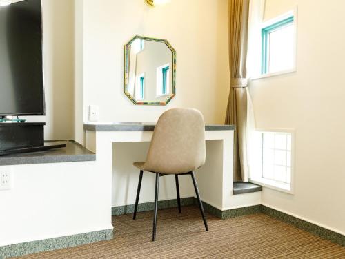 a chair sitting in a room with a mirror at Beppu Kanko Hotel Ace in Beppu