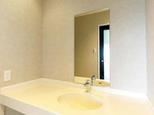 a bathroom with a sink and a large mirror at Beppu Kanko Hotel Ace in Beppu