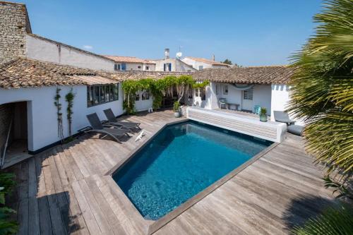 une cour arrière avec une piscine et une terrasse en bois dans l'établissement Charmante maison dans venelle fleurie, à Sainte-Marie de Ré