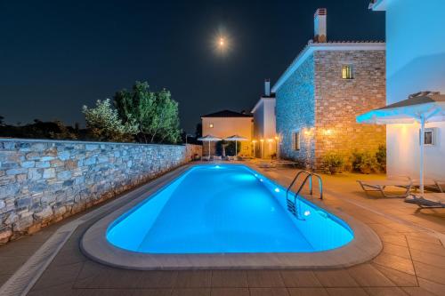 a swimming pool at night with a stone wall at Chroma Pelion Villas in Kato Gatzea