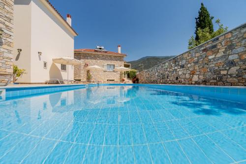 a swimming pool in a villa with a stone wall at Chroma Pelion Villas in Kato Gatzea