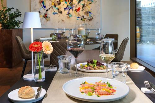 a table with plates of food and glasses of wine at Hotel Lago Maggiore - Welcome! in Locarno