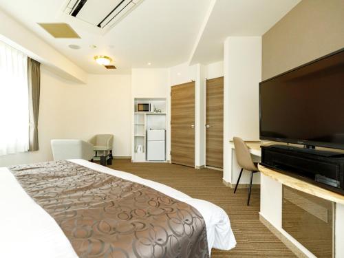a hotel room with a bed and a flat screen tv at Beppu Kanko Hotel Ace in Beppu