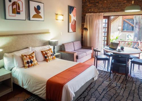 a hotel room with a bed and a chair and a table at Olifants River Lodge by Dream Resorts in Middelburg