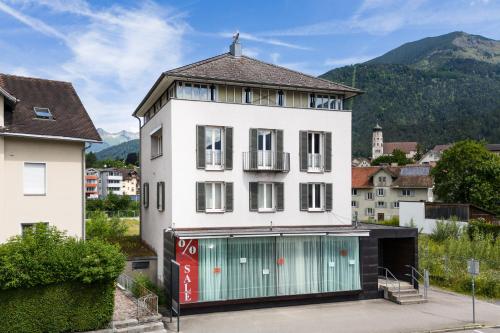 a white building with a green garage at Familienferienwohnung HEIMat in Bludenz
