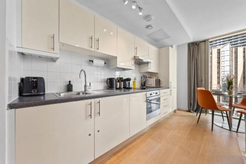 a kitchen with white cabinets and a dining table at Canary Wharf Apartment in London
