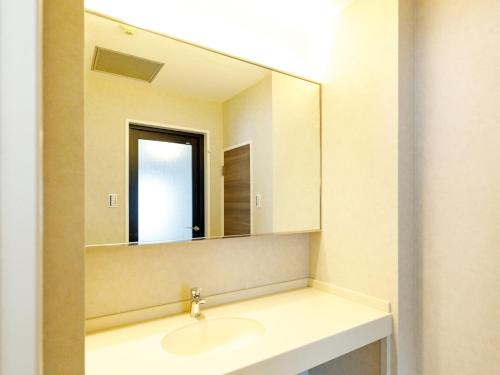 a bathroom with a sink and a mirror at Beppu Kanko Hotel Ace in Beppu