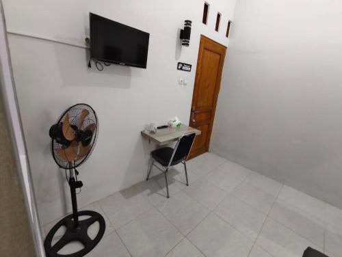a room with a desk and a fan and a television at Livina's House in Mendut