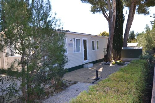 a white house with a tree in front of it at Camping Parc Valrose in La Londe-les-Maures