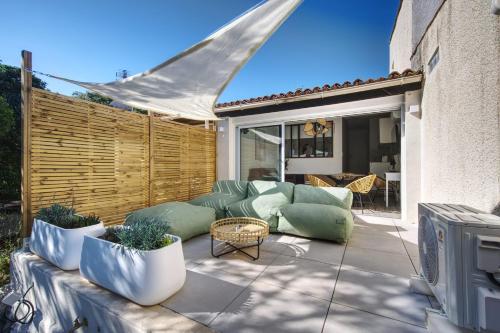 une terrasse avec un canapé, des chaises et une télévision. dans l'établissement Le Mas Emeraude ~ Jardin ~ Parking ~ Climatisation, à Nîmes
