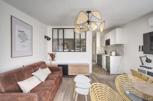 un salon avec un canapé marron et une cuisine dans l'établissement Le Mas Emeraude ~ Jardin ~ Parking ~ Climatisation, à Nîmes