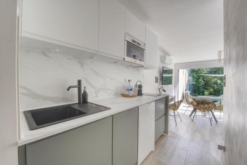 une cuisine blanche avec un évier et une table dans l'établissement Le Mas Emeraude ~ Jardin ~ Parking ~ Climatisation, à Nîmes