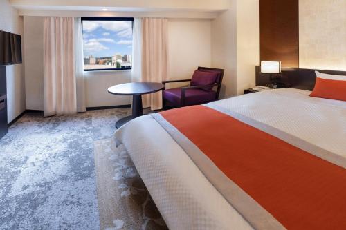 a hotel room with a bed and a chair and a window at Morioka Grand Hotel Annex in Morioka