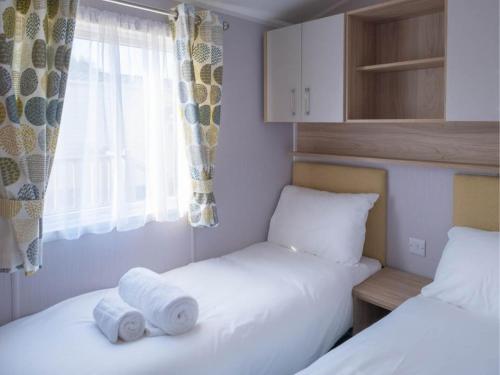 a bedroom with two beds with towels on them at Pinewoods Beach no.5 - sleeps 6 – no dogs in Wells next the Sea