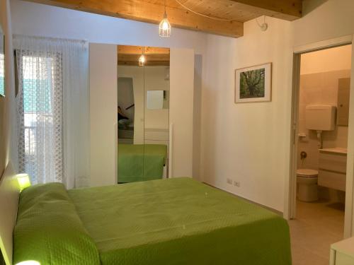 a bedroom with a green bed and a mirror at Casa Gaia, La Casa Sui Tetti in Isolabona