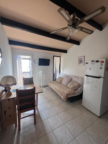 - un salon avec un canapé, une table et un réfrigérateur dans l'établissement Studio Aigues Mortes avec parking gratuit, à Aigues-Mortes