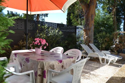 a table and chairs with an umbrella and flowers on it at Camping Parc Valrose in La Londe-les-Maures