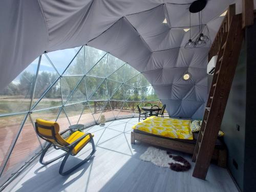a room with a tent with a bed and chairs at Ēdelveisi Lauku sala in Līvbērze