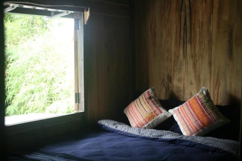 a bed with two pillows in a room with a window at Sa Moc - La Maison House & Bungalow in Sa Pa