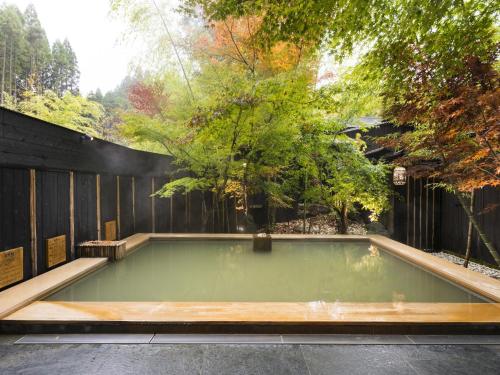 a pool of water in a backyard with trees at Hikyou Shirakawagensen Sansou Takefue in Minamioguni