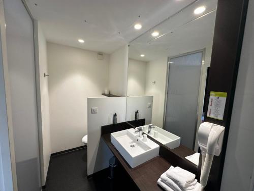 une salle de bain avec un lavabo blanc et un miroir dans l'établissement Hôtel Gardenia Bordeaux Est, à Yvrac