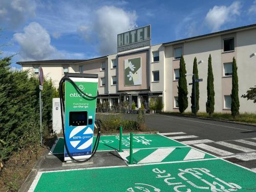a hotel with a charging station in front of a building at Hôtel Gardenia Bordeaux Est in Yvrac