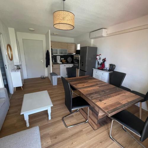 Il dispose d'une cuisine et d'un salon avec une table et des chaises en bois. dans l'établissement Maison plain pied avec climatisation dans une résidence privée avec piscine, à Saint-Saturnin-lès-Avignon