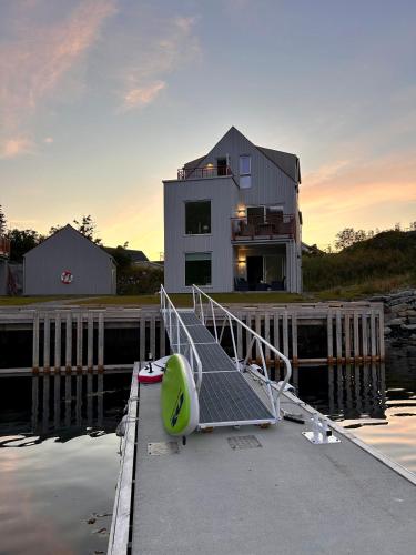 a dock with a house in the water with a boat at #Lofoten Leilighet ved sjøen in Ballstad