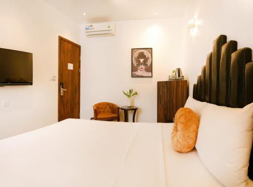 a bedroom with a white bed and a television at Rosa Hanoi Hotel in Hanoi