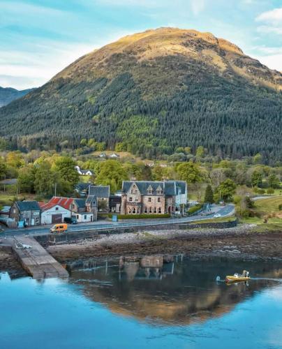 a town next to a body of water with a mountain at The Ballachulish Hotel in Glencoe