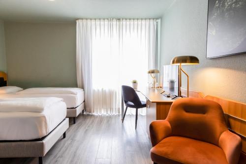 a hotel room with two beds and a desk and a chair at Mercure Hotel Pforzheim in Pforzheim