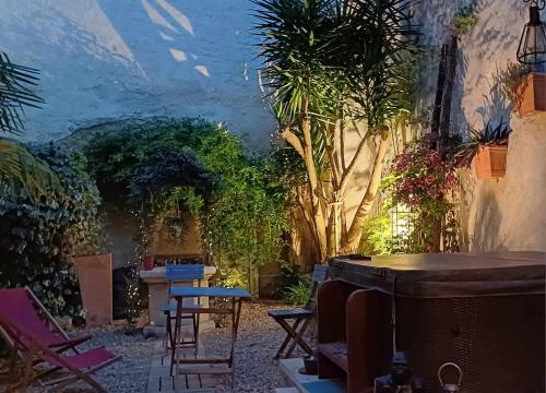 a patio with chairs and a table and trees at Maison de caractère au coeur des vignes et du Canal du Midi in Capestang