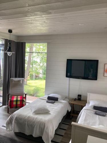 a bedroom with two beds and a flat screen tv at Moderni rantasauna ja -mökki in Joensuu