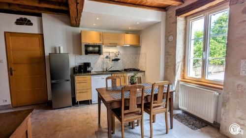 una cucina con tavolo, sedie e frigorifero di Au bout du Ciel - Maison avec garage, terrasse, cave a Savigny-lès-Beaune