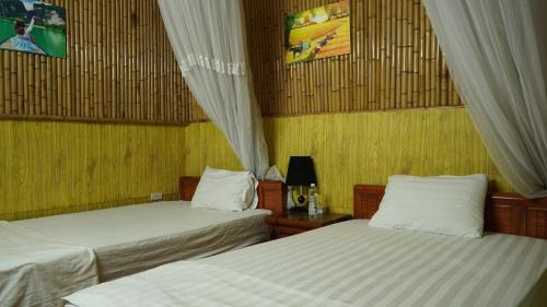 two beds in a room with yellow walls at Hoa lu Eco Homestay in Ninh Binh