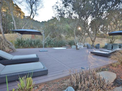 a wooden deck with chairs and umbrellas in a garden at Chateau Crystal in Dullstroom