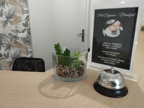 a vase with a plant in it on a table at Brit Hotel L'Arrivée Guingamp in Guingamp