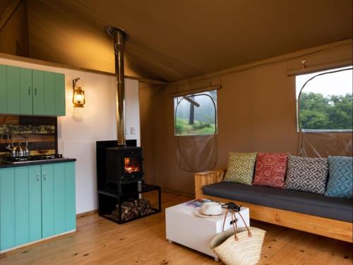 a living room with a couch and a stove at AfriCamps at Milorho in Rustenburg