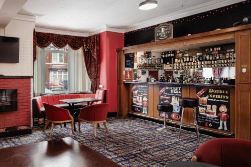 a bar with red walls and a table and chairs at Lanayr Hotel in Blackpool