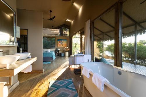 a large bathroom with a tub and two sinks at Chundu Island in Victoria Falls