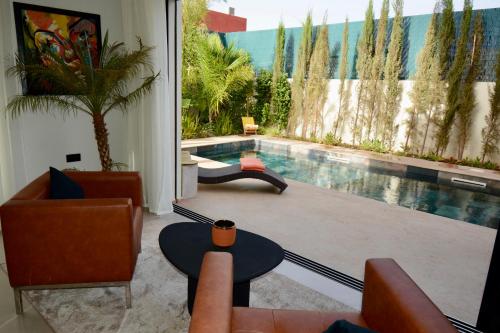 a living room with a pool with chairs and a table at Somptueuse Family Villa Cherifa avec piscine in Marrakech