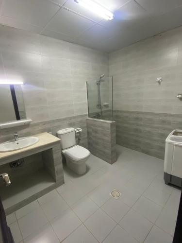a bathroom with a toilet and a shower and a sink at Jawhrat Furnished Apartment in Salalah