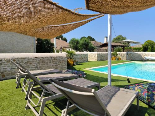 une terrasse avec des chaises et un parasol ainsi qu'une piscine dans l'établissement LES BOHEMIELLES Cottage Raphaël, à Cartelègue