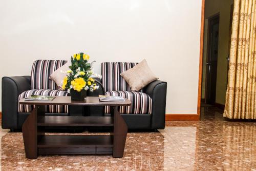 a living room with a couch and a coffee table with flowers at Hotel Nilketha Yala Tissamaharama in Tissamaharama