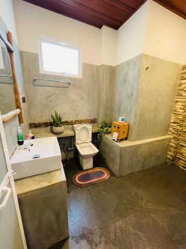 a bathroom with a toilet and a sink and a tub at Dhanudi Homestay in Ella