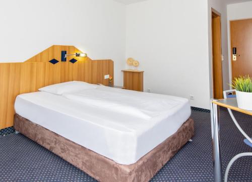 a bedroom with a large bed with a wooden headboard at Mercure Hotel Pforzheim in Pforzheim