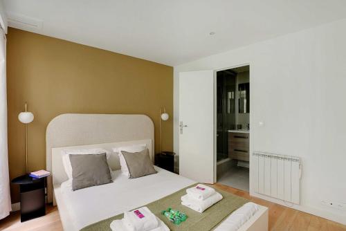 une chambre avec un lit blanc avec des serviettes dessus dans l'établissement Magnificent apartment - 1BR-4P - Palais Royal, à Paris