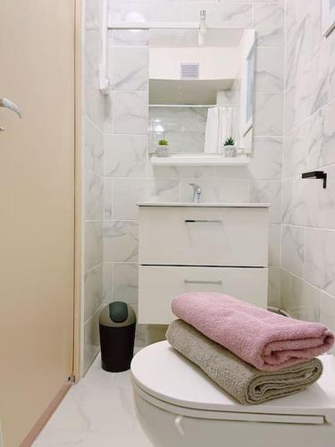 une salle de bain blanche avec une serviette rose sur les toilettes dans l'établissement 711 Appart versatile proche du Métro et Paris 20E, à Bagnolet